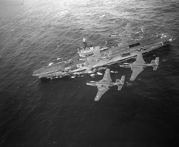 hree aircraft fly over a naval ship.